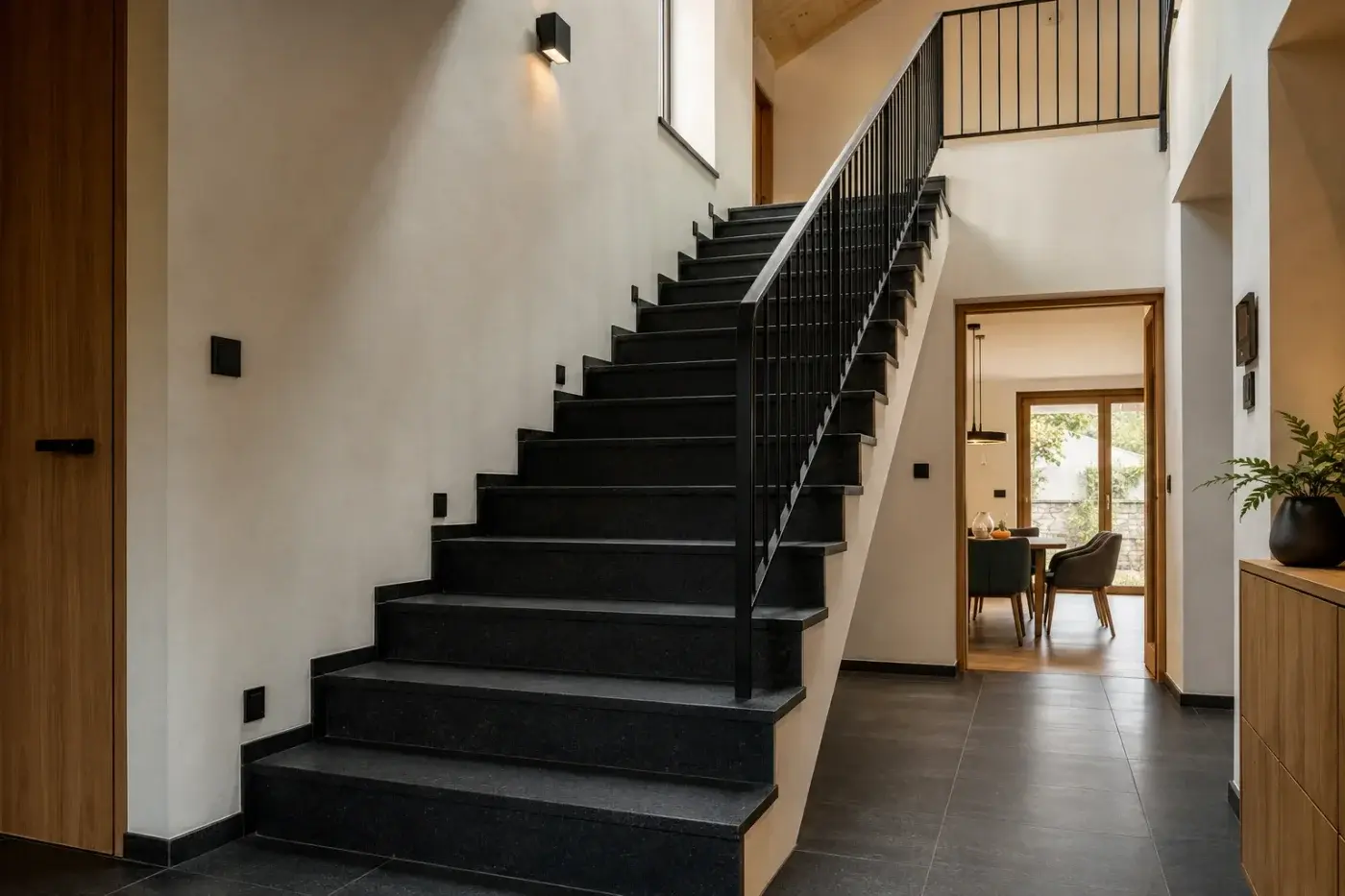 Schody wewnętrzne z ciemnego granitu z metalową balustradą
