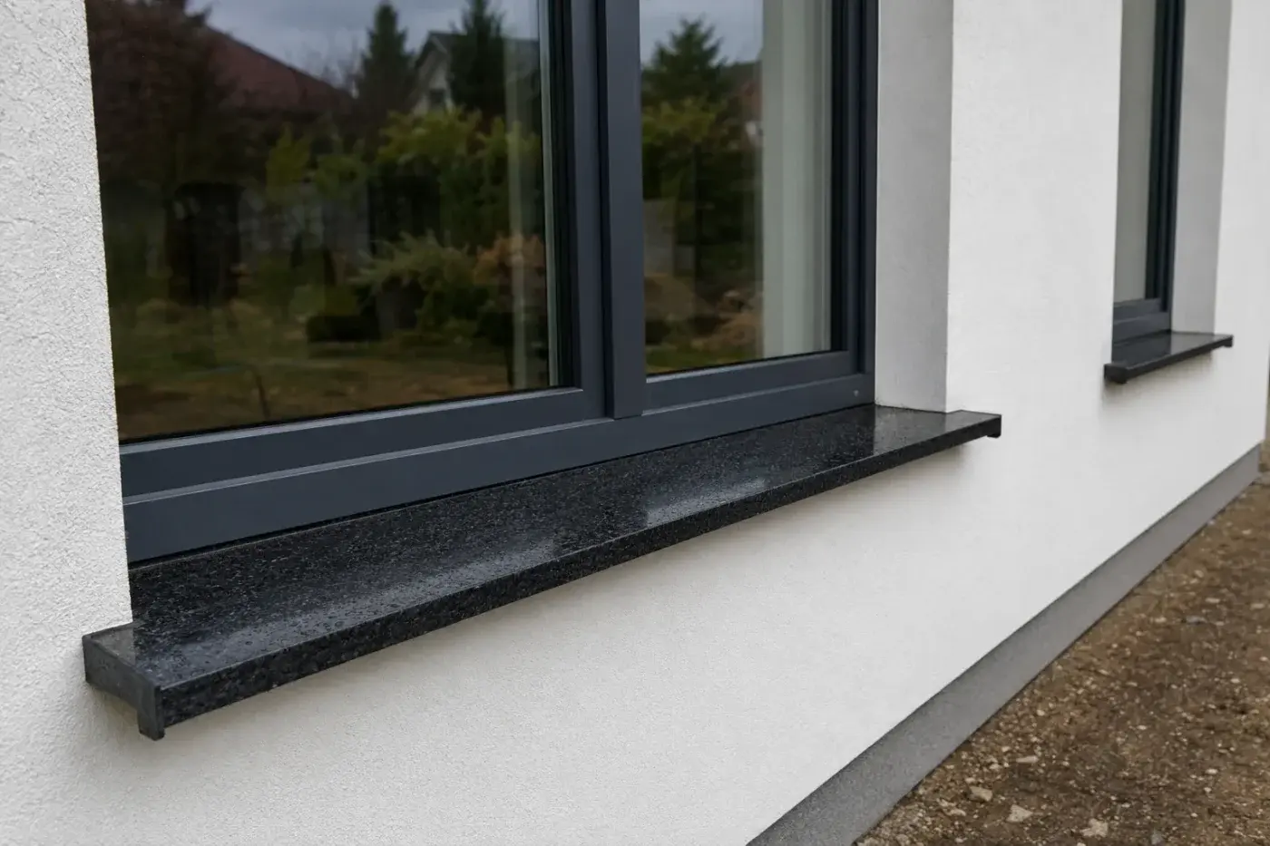Parapet zewnętrzny z czarnego granitu na jasnej elewacji przy ciemnym oknie — realizacja LEMSTONE