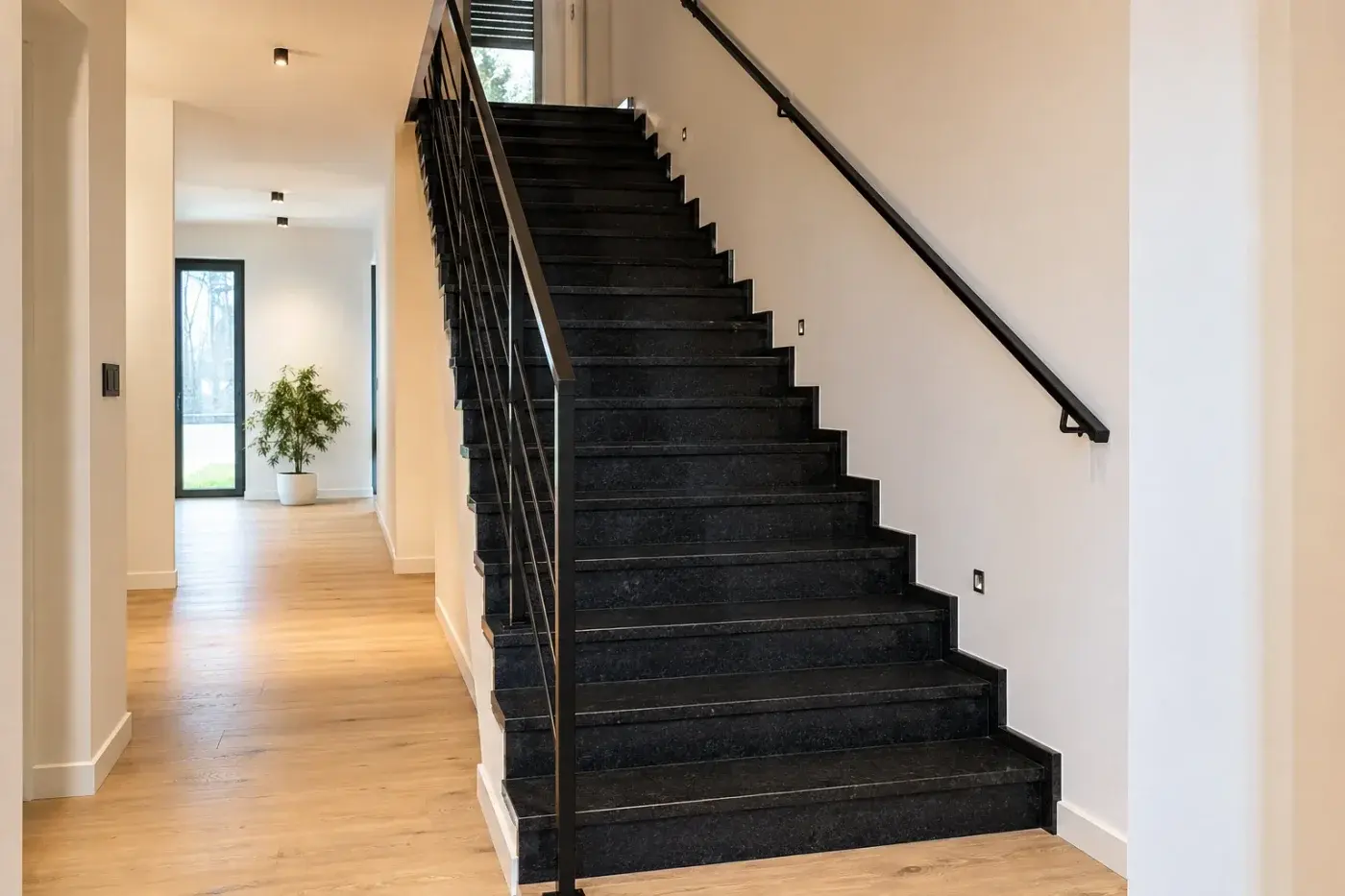 Schody wewnętrzne z czarnego granitu z metalową balustradą w jasnym wnętrzu — realizacja LEMSTONE
