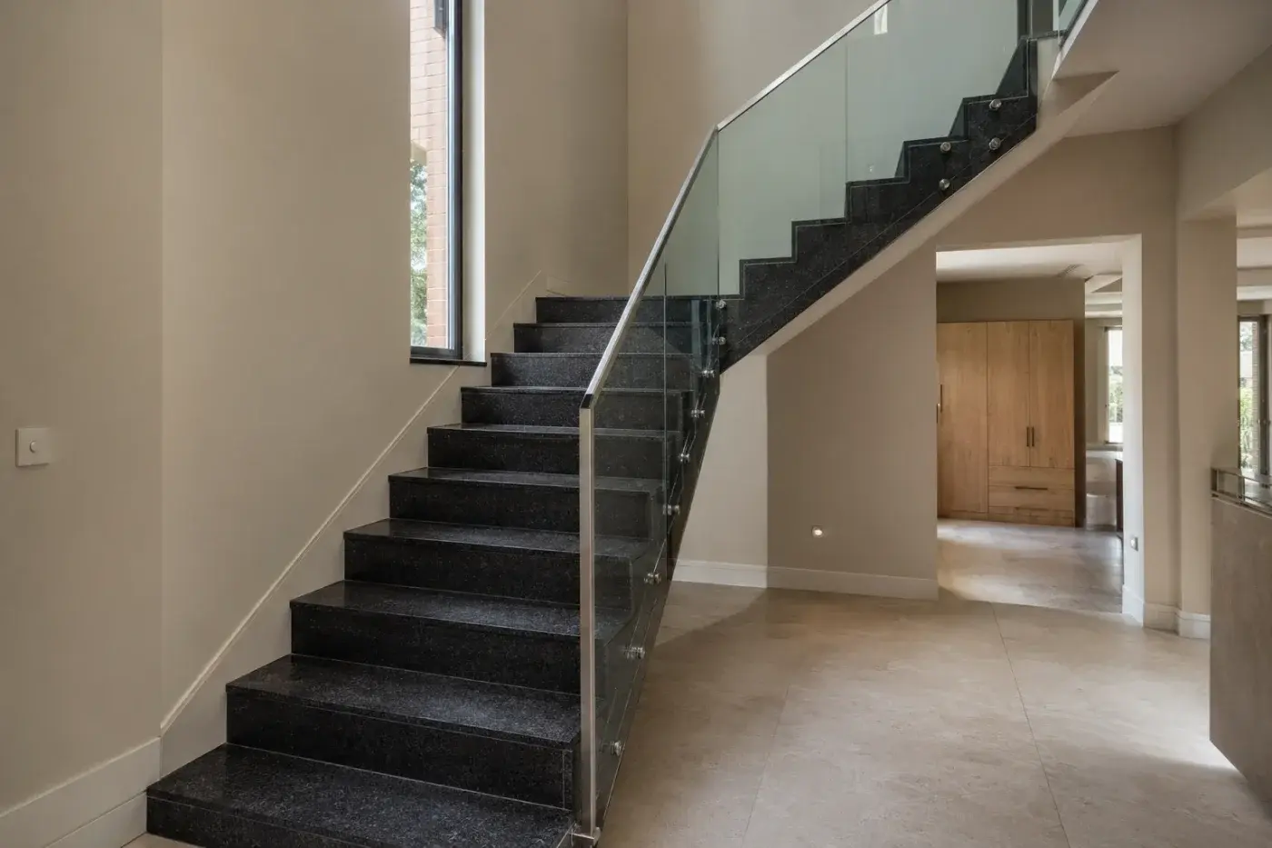 Schody wewnętrzne z czarnego granitu ze szklaną balustradą — realizacja LEMSTONE